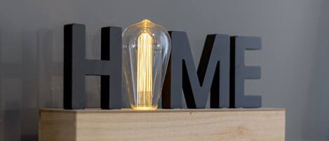 A clear glass light bulb on a wooden block with the letters "HOME" in black behind it.