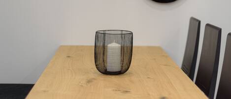 A dining table with a black wire basket and wooden chairs.