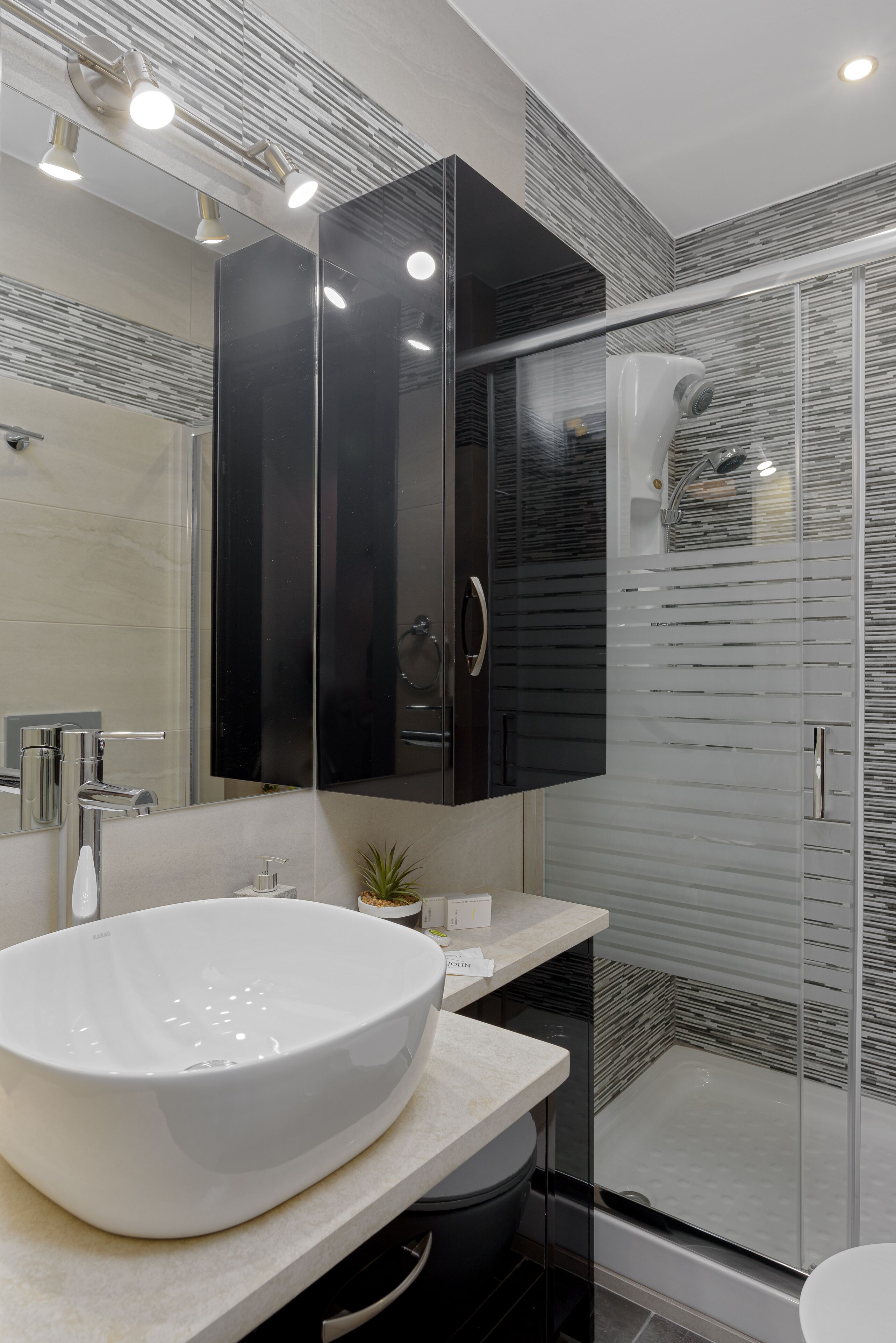 A modern bathroom with a large white sink, a mirror, and a glass-enclosed shower.