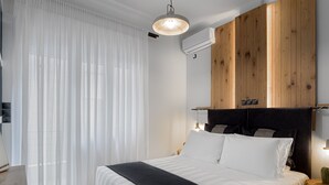 A modern bedroom with a large bed, wooden headboard, and a ceiling light. - Acropolis Deluxe Apartment (Athens)
