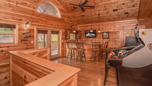 L’intérieur d’un chalet en bois comprend un bar, des sièges et un téléviseur.