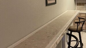 Eine Küche mit langer Arbeitsfläche, einem gerahmten Bild an der Wand und Holzschränken.