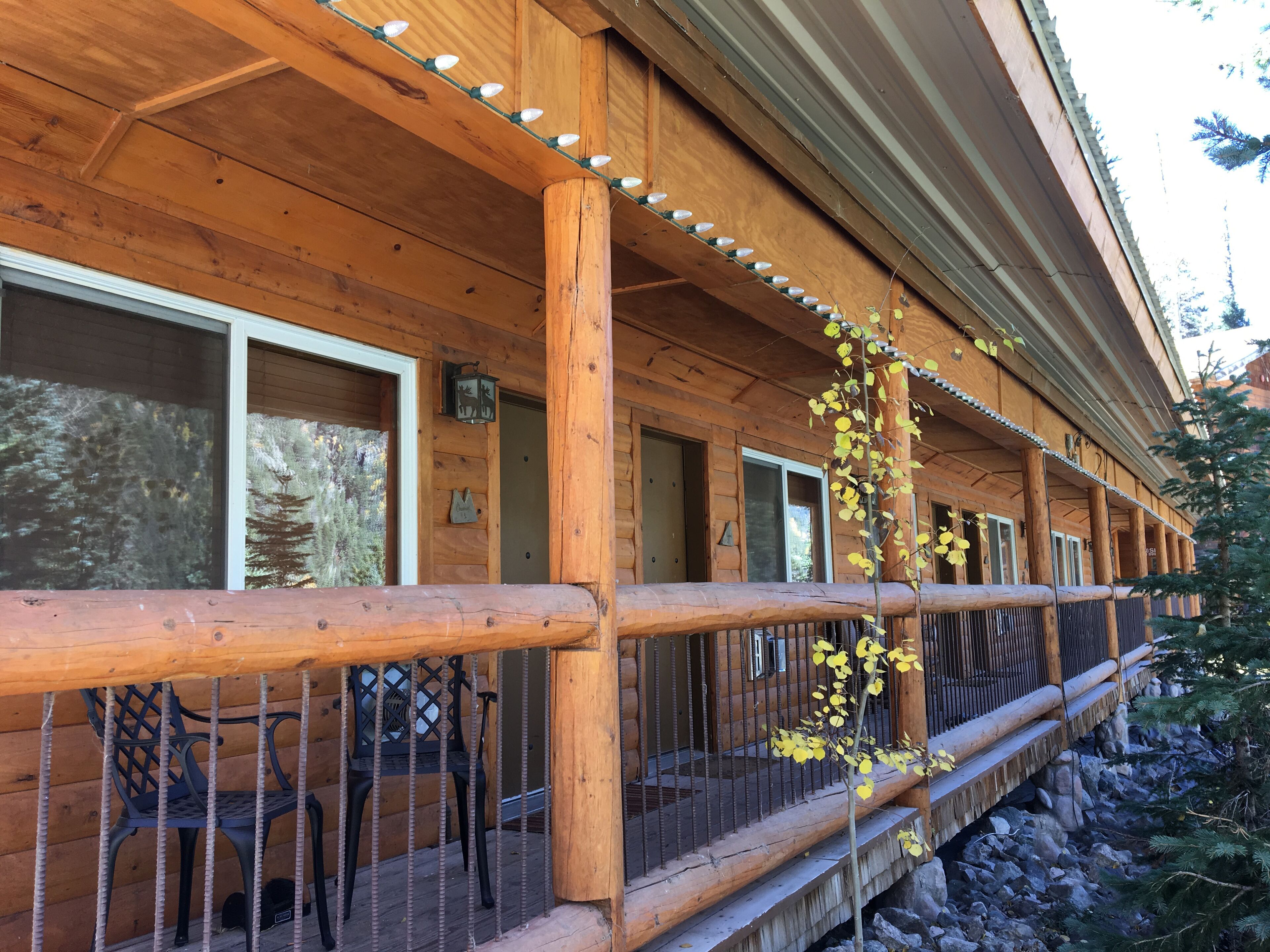 A wooden cabin with a porch, a railing, and a small table with chairs.