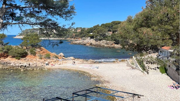 Une zone côtière caractérisée par des eaux limpides, un terrain rocheux et une plage.