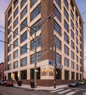 A multi-story building with a corner entrance, large windows, and a sign for 'Brand New Apparel'. - Sosuite | 1BR Penthouse w W/D, Gym, On-Site Bar (Philadelphia)