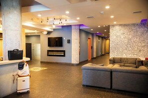 A lobby with a reception desk, a flat-screen TV, a fireplace, and a seating area. - Sosuite | 1BR Penthouse w W/D, Gym, On-Site Bar (Philadelphia)