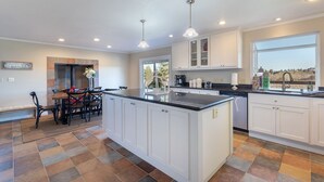 A modern kitchen with white cabinetry, a central island, and a dining area with chairs and a table.