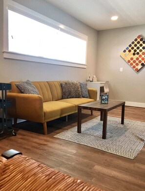 Relax in this stylish living room with a sofa, coffee table, and rug, perfect for unwinding and enjoying a meal.