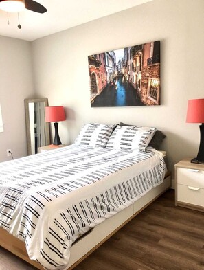 Cozy retreat with a large bed, bedside tables, and a framed photograph of a canal scene.
