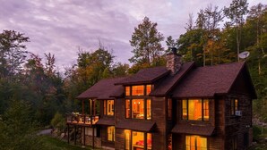 A two-story log cabin with multiple windows and a deck, surrounded by trees. - Maine Stay- Contemporary Mountain Home, Spectaular Outdoor Space! (Newry)
