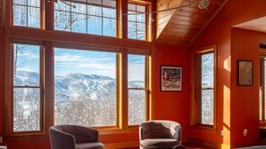 A room with large windows offering a mountain view, a wooden ceiling, and a cozy seating area with a rug. - Maine Stay- Contemporary Mountain Home, Spectaular Outdoor Space! (Newry)