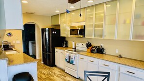 Une cuisine moderne dotée de plans de travail en granit, d’appareils électroménagers en acier inoxydable et de meubles blancs.