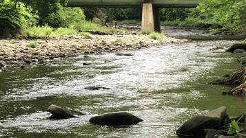 Un río con rocas y un puente al fondo.