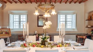 A dining room with a table set for a meal, featuring white tablecloths, candles, and fruit. - Villa BRUNETTA, Discover your Modern but Traditional Villa in Lucca (Capannori)