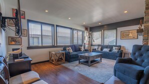 A spacious living room with a large sectional sofa, a coffee table, and a television mounted on the wall. - Edgewater #20 - 2 BD/2 BTH (June Lake)