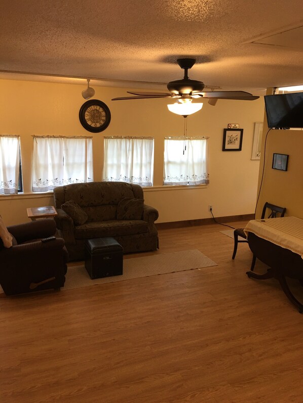A room with a ceiling fan, a sofa, a small table, and a bed.