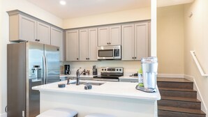 A modern kitchen with a stainless steel refrigerator, a microwave, and a coffee maker.