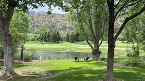 Un campo de golf con un estanque, árboles y dos sillas.
