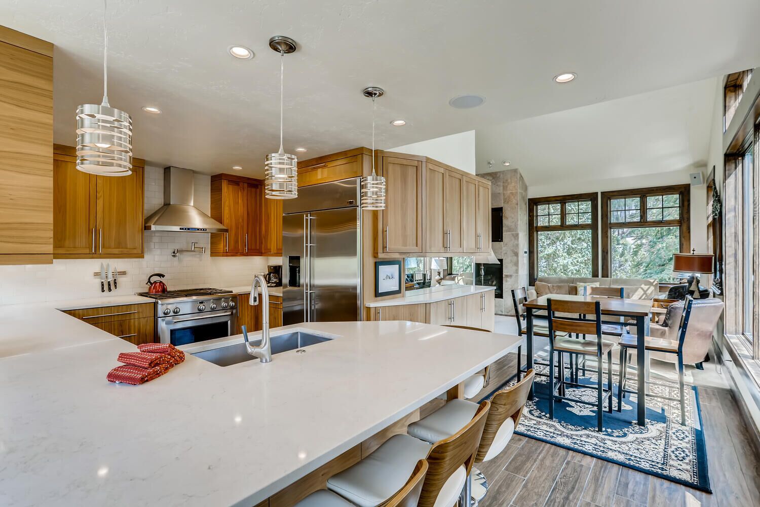 Una cocina moderna con armarios de madera, electrodomésticos de acero inoxidable, una isla grande con taburetes y vistas al exterior.