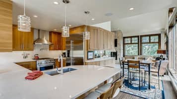 Una cocina moderna con armarios de madera, electrodomésticos de acero inoxidable, una isla grande con taburetes y vistas al exterior.