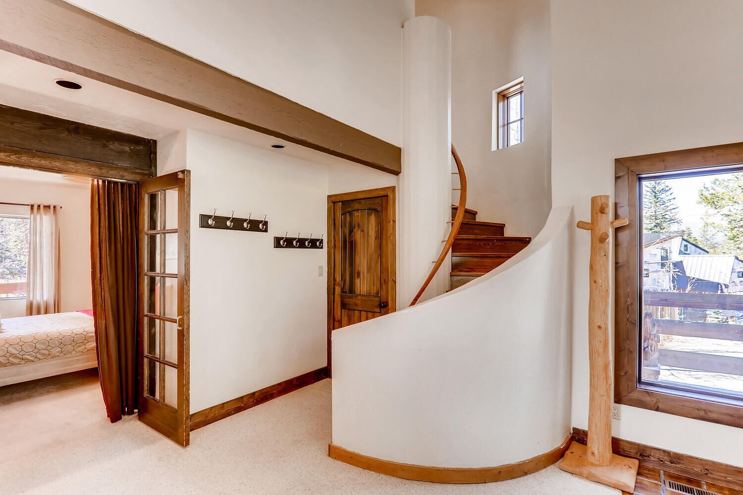 Una escalera de caracol en una habitación con una cama, un perchero y una ventana con vistas al exterior.