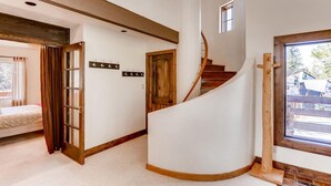 A spiral staircase in a room with a bed, a coat rack, and a window with a view of the outside. - Wellington Haus: Dog Friendly Home, Hot Tub, Views (Breckenridge)