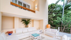 A spacious living area with white furniture, a patterned rug, and a view of lush greenery. - Gated Ocean View Villa with Direct Beach Access (Huatulco)