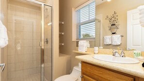 Un baño con cabina de ducha de vidrio, un lavabo con tocador y un inodoro.