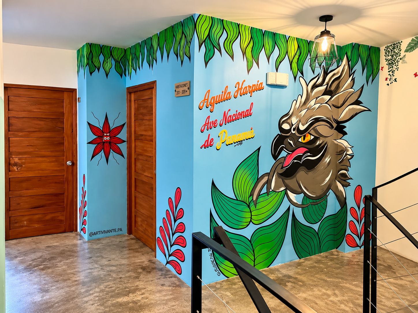 Un pasillo con un mural de un jaguar, una puerta de madera y un letrero que indica el número de habitación.