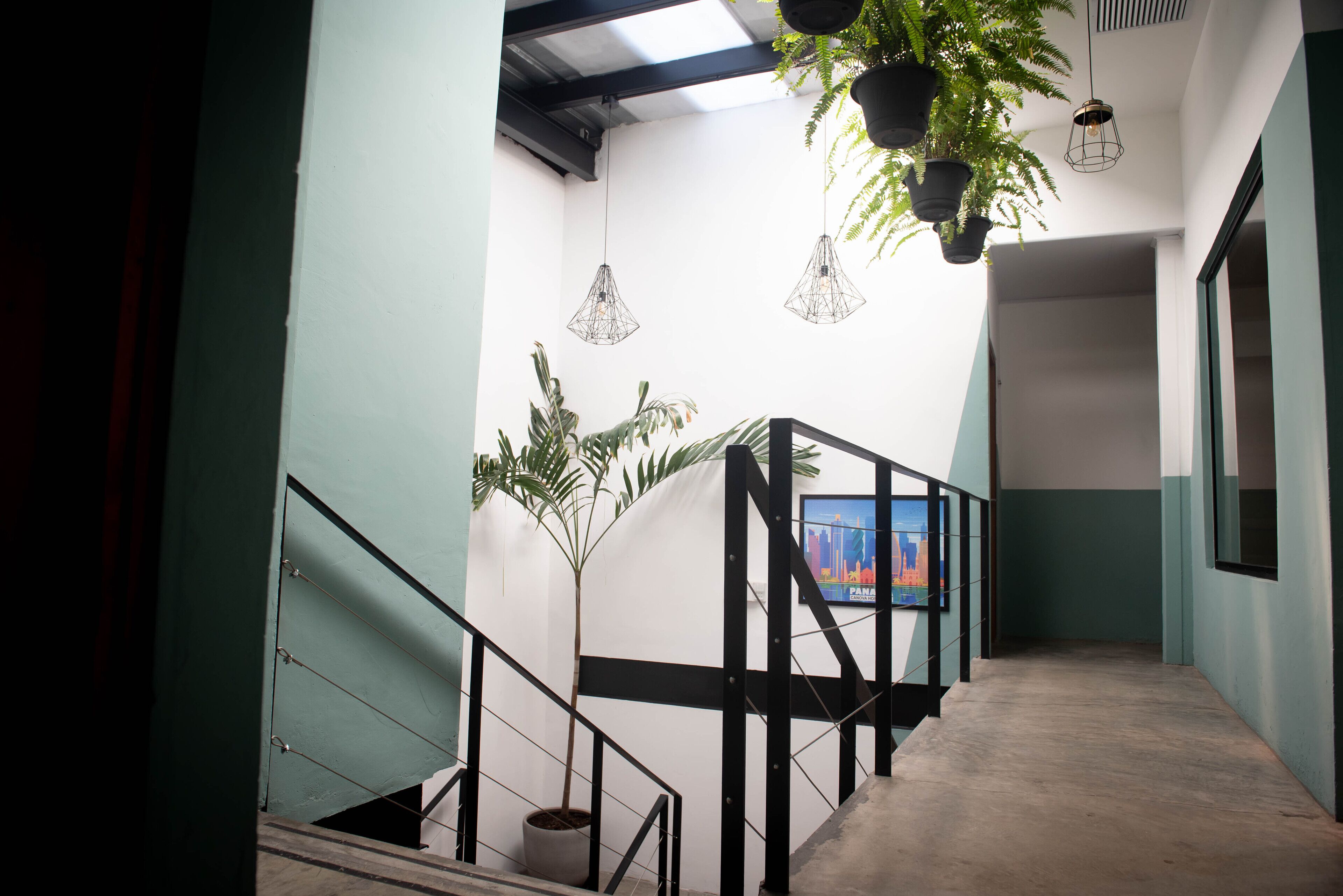 A modern interior with a staircase, potted plants, and pendant lighting.