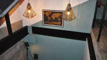 A staircase with a framed world map and two hanging light fixtures.