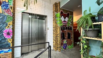 Ascensore con graffiti sui muri, una scala e piante in vaso.