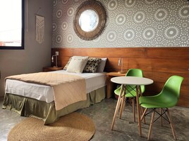 Un dormitorio con cama, mesita de noche, lámpara y un espejo redondo en la pared.