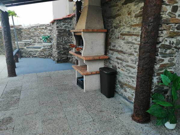 Un muro de piedra con una parrilla incorporada y un contenedor de basura.
