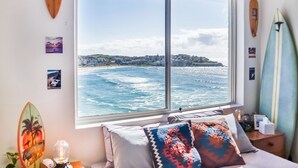 Una stanza con un'ampia finestra che si affaccia sull'oceano e su un panorama urbano in lontananza.