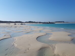 A beach with clear water and sand patterns.
