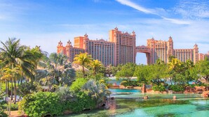 Een resort met meerdere hoge gebouwen, een grote bogenpoort en een zwembadgedeelte omringd door palmbomen.