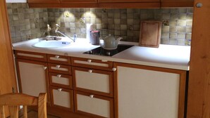 A kitchen with wooden cabinets, a white countertop, a sink, a kettle, and a toaster. - Ferienwohnung, 55 qm Obergeschoss, 1 Separates Schlafzimmer (Bad Endorf)