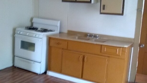 A small kitchen with a white stove, wooden cabinets, and a wooden countertop.