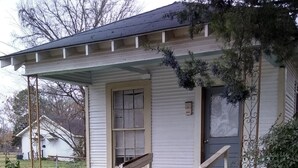 A small, single-story house with a porch, a door, and a window.