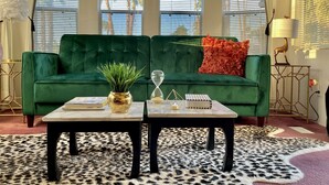 Ein grünes Sofa, ein Couchtisch, ein Blumentopf und eine dekorative Sanduhr.