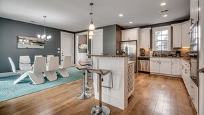 Een moderne keuken met witte kasten, roestvrijstalen apparatuur en een centraal kookeiland met barstoelen.