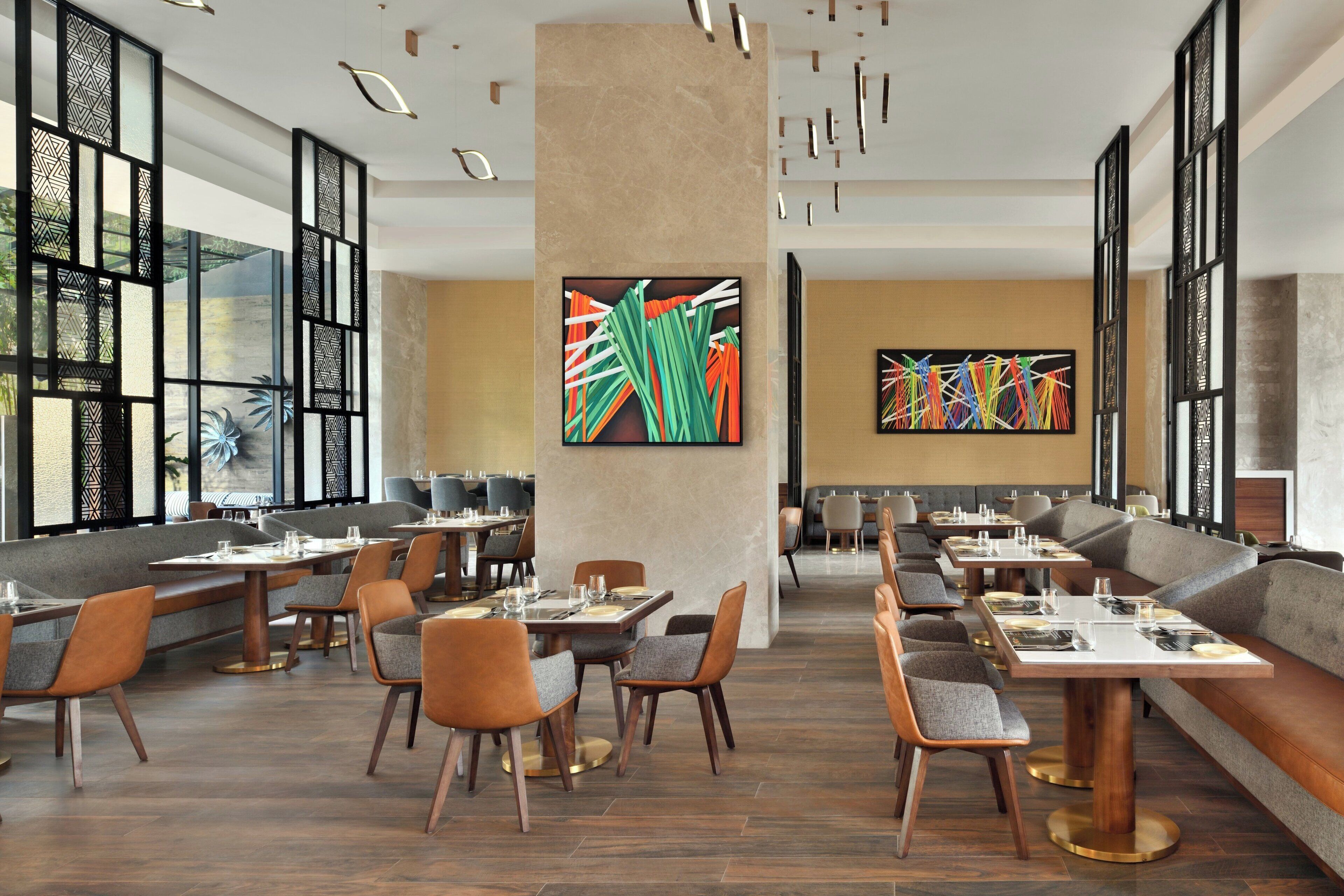 Un restaurant moderne avec de hauts plafonds, un plancher en bois et un mélange de banquettes et de tables.