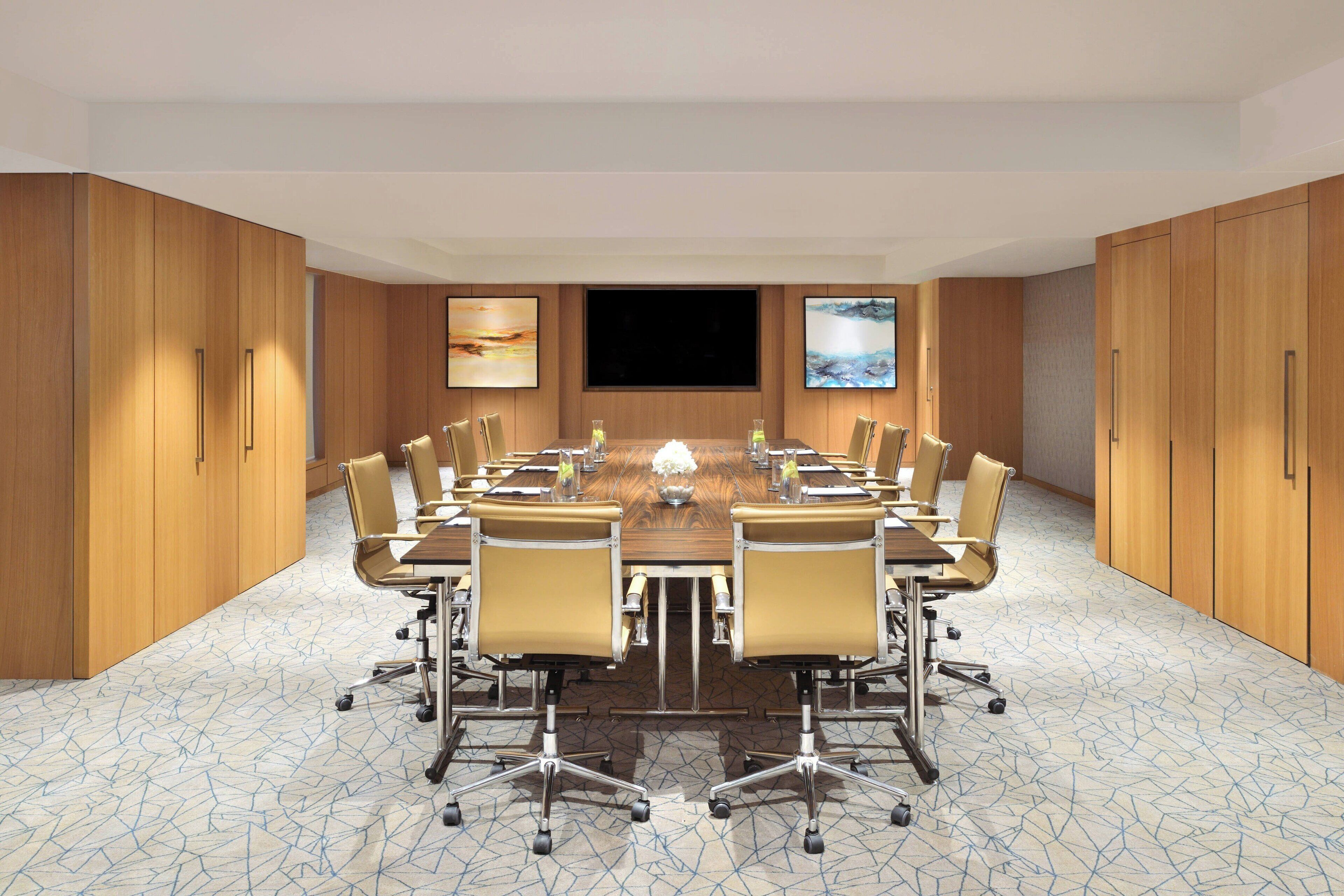 A conference room with a large table, chairs, and a TV screen.