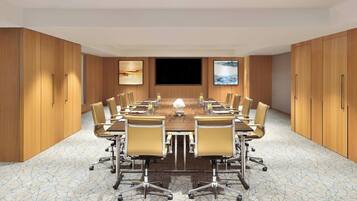 A conference room with a large table, chairs, and a TV screen.