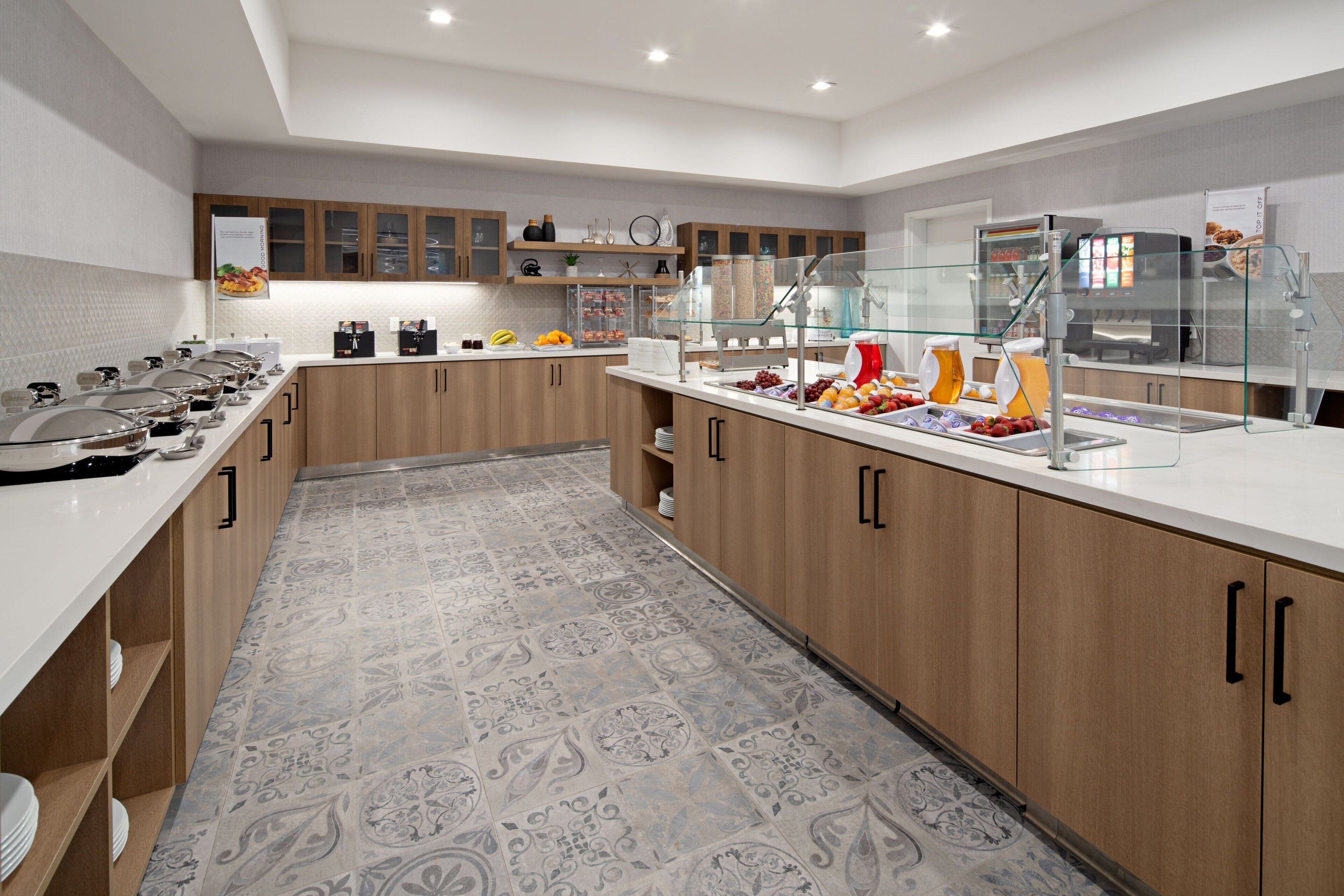 A modern kitchen with a buffet setup, including a glass display case and various food items.