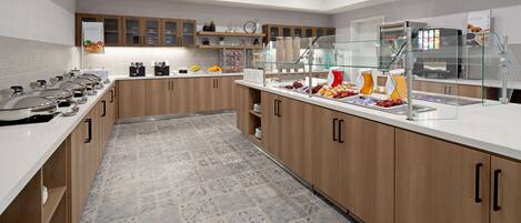 Una cocina moderna con una barra de buffet, que incluye un expositor de vidrio y diversos alimentos.