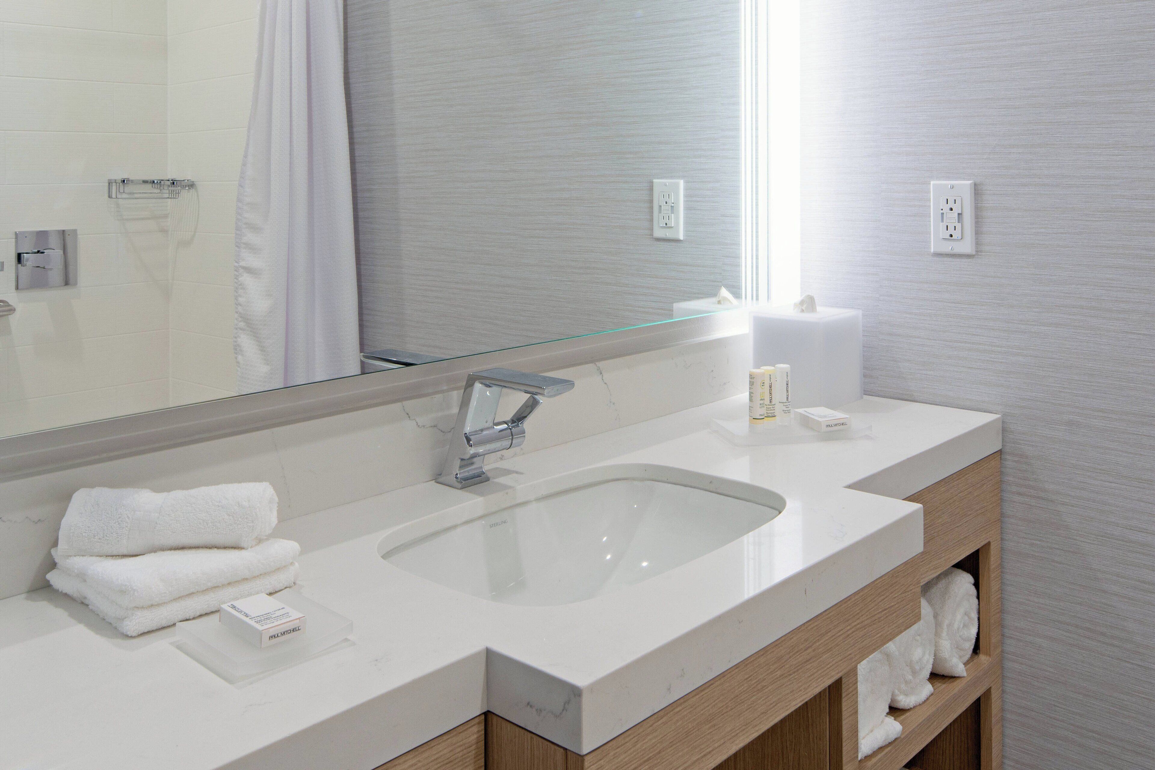 A modern bathroom with a large mirror, two sinks, and a glass shower enclosure.