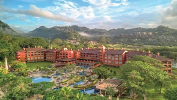 Un gran hotel con varias construcciones, un patio central con piscinas y abundante vegetación alrededor de la propiedad.