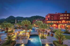 A resort with a swimming pool, palm trees, and a bridge. - Marriott Vacation Club at Los Suenos (Jacó)